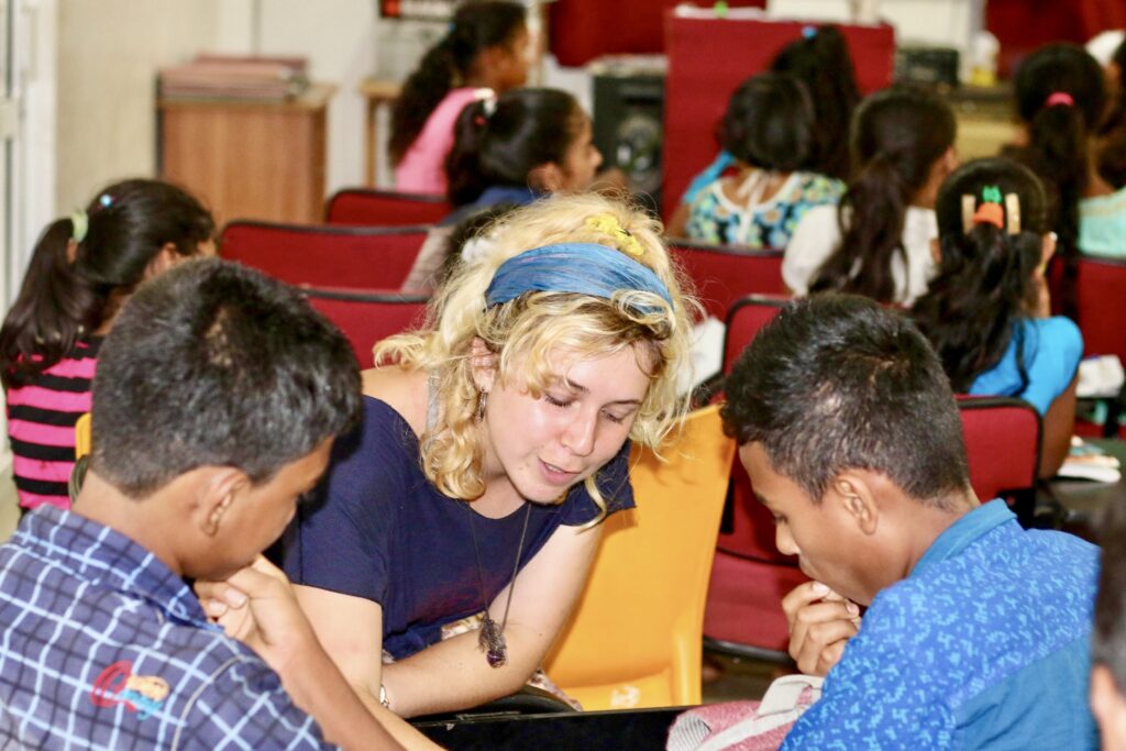 A volunteer helping two students with their work